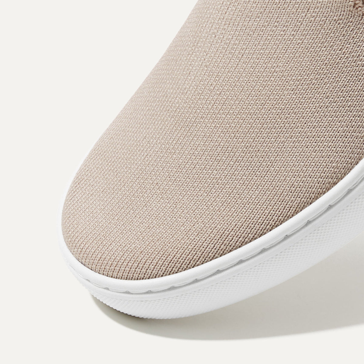The slip-on Sneaker in Sand shown from the top view with detailing of the front of the shoe.