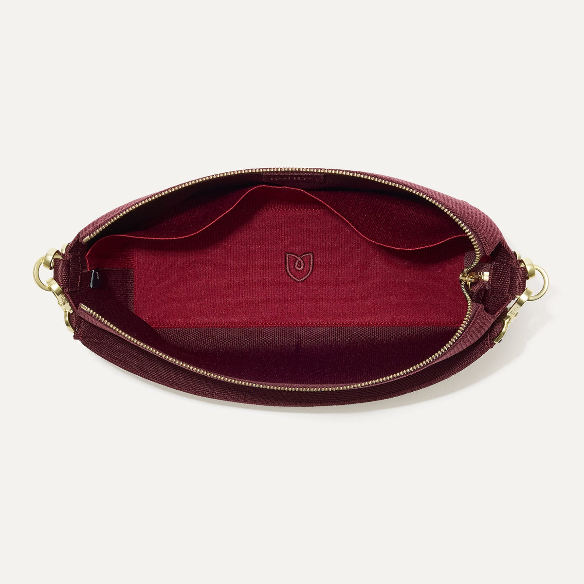 The Daily Crossbody in ReVelvet™ Syrah, shown from the top down, with zipper open and interior exposed.