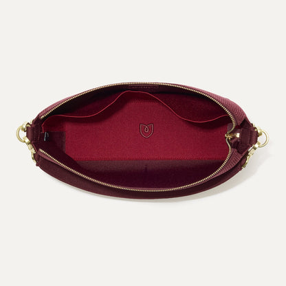 The Daily Crossbody in ReVelvet™ Syrah, shown from the top down, with zipper open and interior exposed.