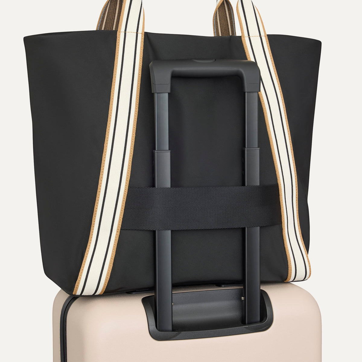 The Travel Tote in Ink, shown attached to a rolling suitcase using the wrap-around band.